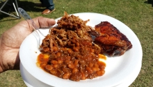 pulled pork, bbq chicken and red beans on a white styrofoam plate