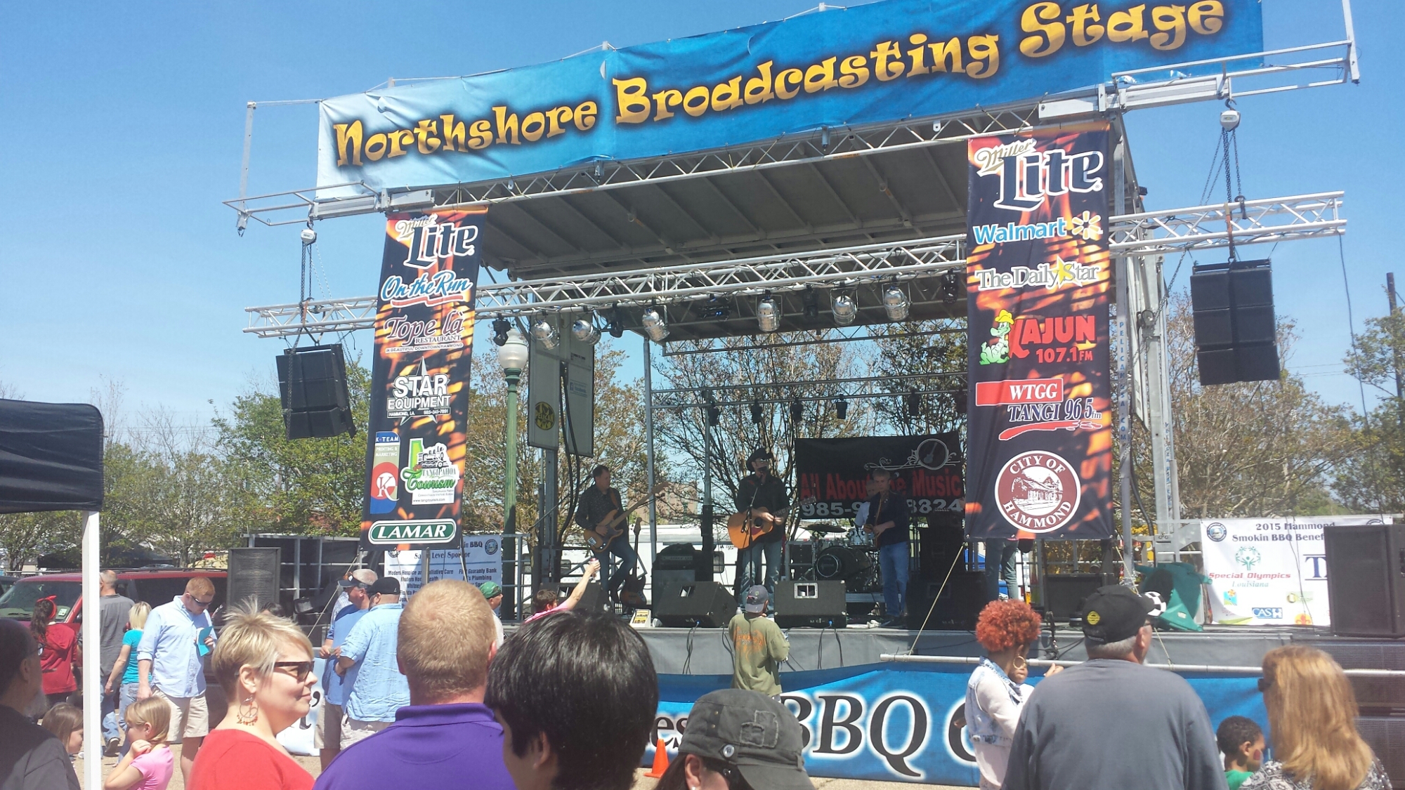 a stage with a five piece band and a banner on top "Northshore Broadcasting Stage"
